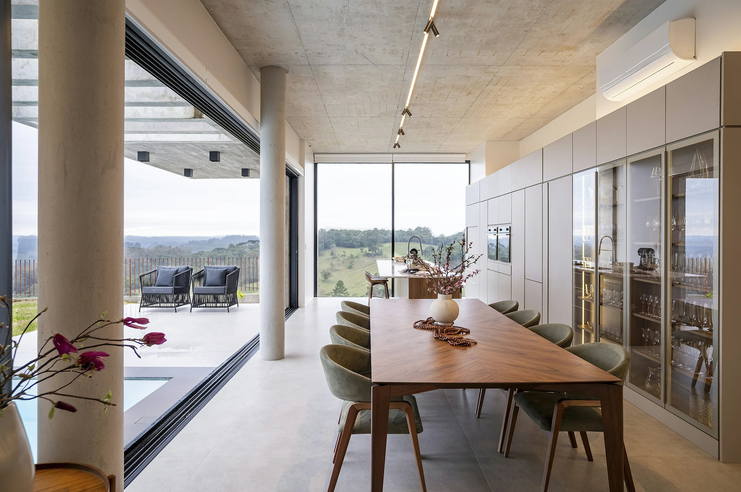 A long dining table in an open room with floor-to-ceiling windows