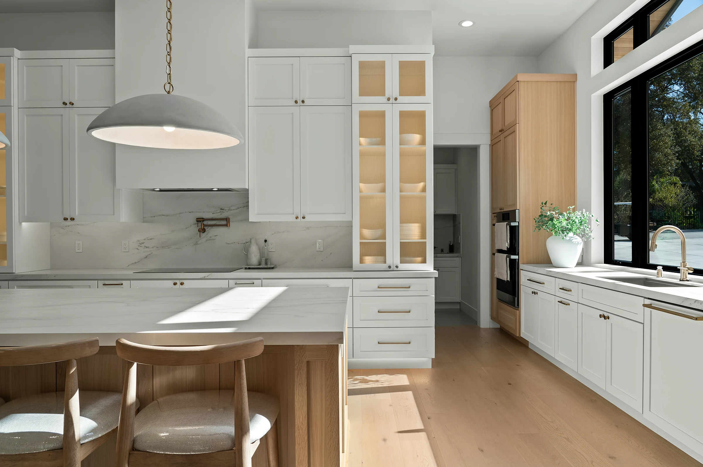 A bright white kitchen with clear counters and a wooden island