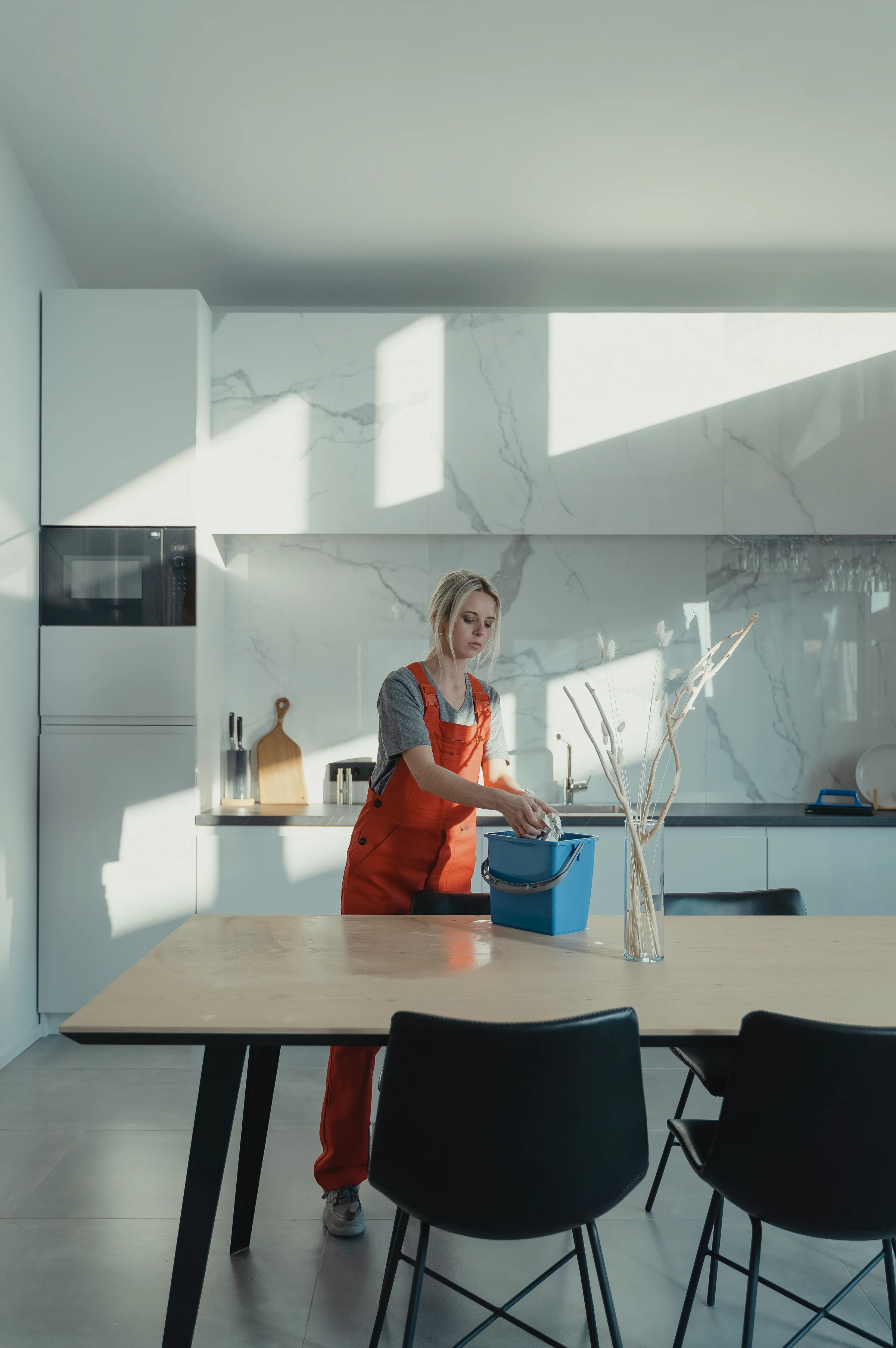 A cleaner in overalls working at the kitchen sink of an empty home