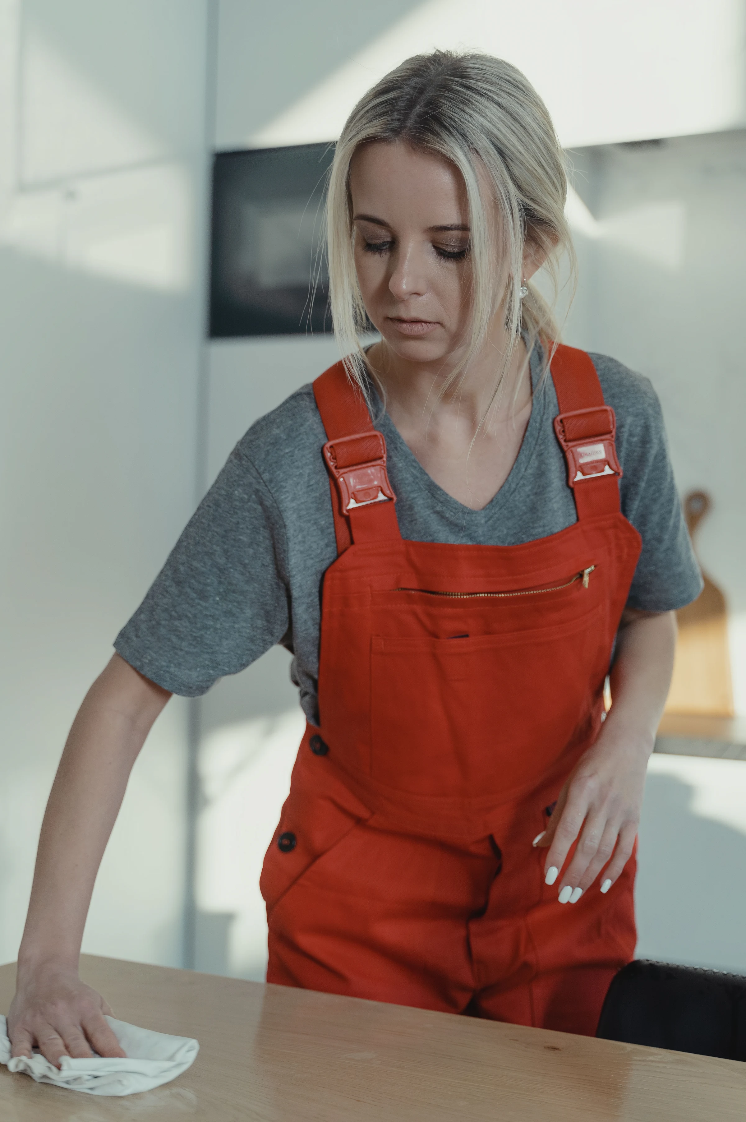 A cleaner in overalls wiping down a table